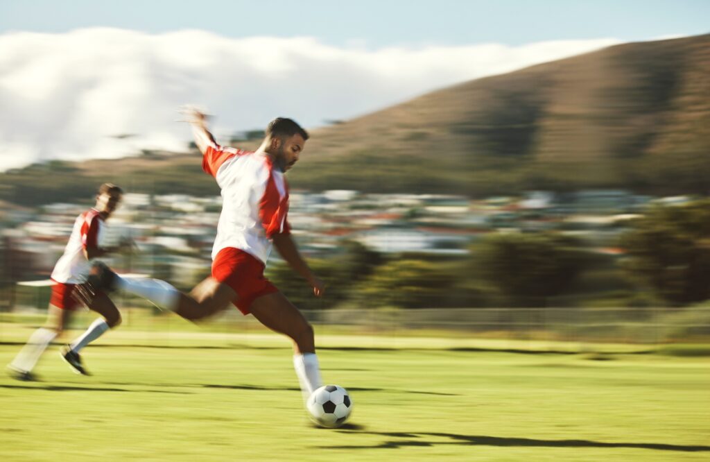 Energy, fitness and soccer training with soccer playing in power kick with ball on a soccer field f